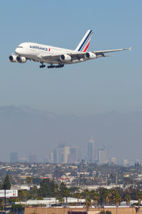 Airplane flying over city against sky