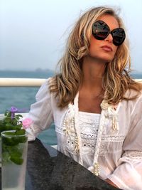 Woman wearing sunglasses at restaurant against sea