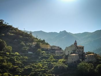 Buildings by mountains against clear sky