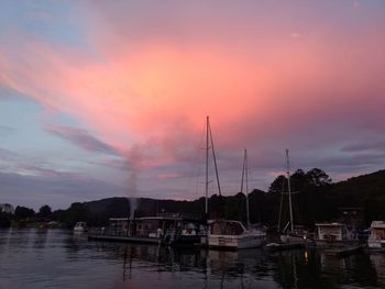 Sailboats moored at harbor during sunset