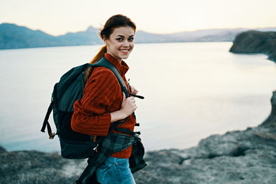 Portrait of smiling young woman standing at sea shore