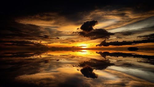 Scenic view of sea against dramatic sky during sunset