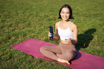 Portrait of young woman exercising on field