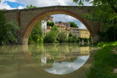 Arch bridge over river against sky