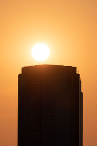 Low angle view of silhouette building against orange sky