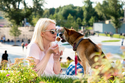 Woman wearing sunglasses feeding dog
