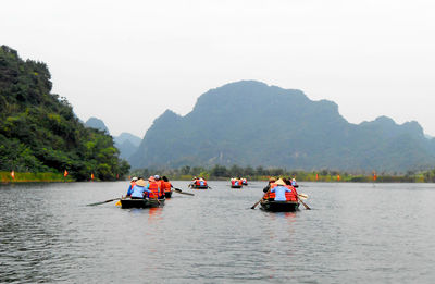 People on boat in river against sky