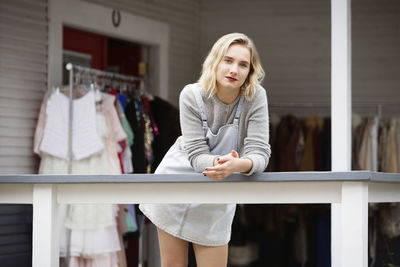 Portrait of woman leaning on railing at boutique