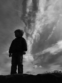 Low angle view of silhouette boy standing against sky