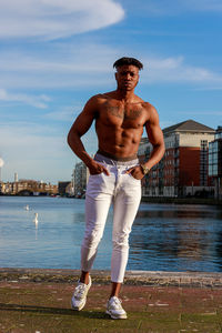Rear view of shirtless man standing at beach against sky