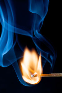 Close-up of burning matchstick against black background