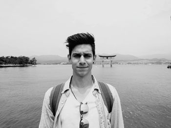 Portrait of young man standing against sea