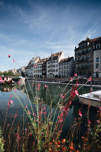 Buildings by lake against sky in city