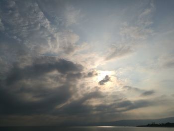 Low angle view of sunlight streaming through clouds