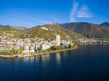 Scenic view of lake by buildings in town against sky