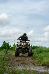 Man riding atv on plants against sky