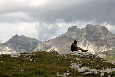 Woman sitting on rock against mountains