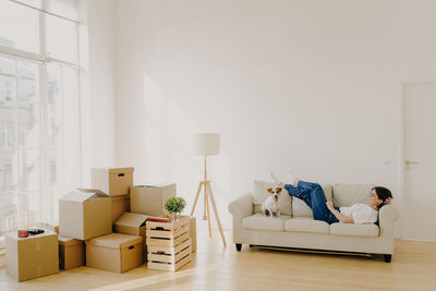 Woman with dog relaxing on sofa in new house