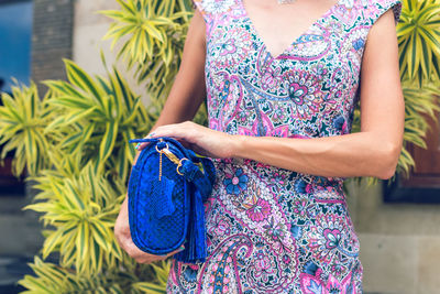 Midsection of woman standing against purple wall