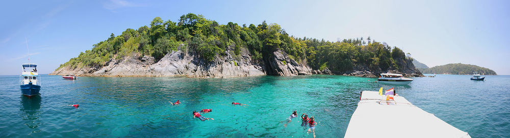 People swimming in pool by sea against sky