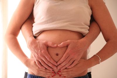 Midsection of man touching stomach of pregnant woman