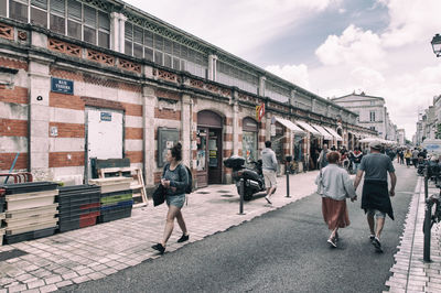 People walking on street in city against sky