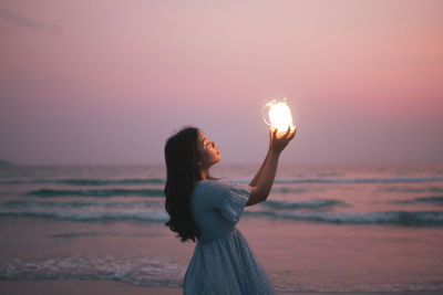 Woman standing at beach during sunset