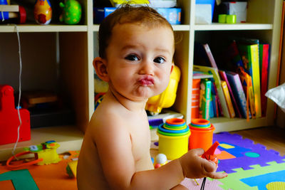 Cute baby girl holding toy while sitting at home