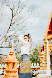 Woman standing by temple against trees