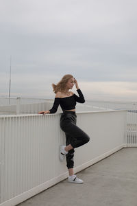 Full length of woman standing on railing against sky