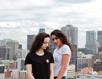 Smiling young woman against modern cityscape against sky