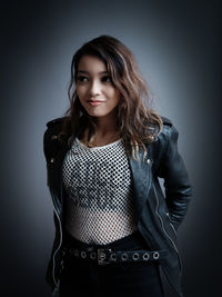 Portrait of young woman against black background