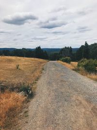 Road amidst field against sky