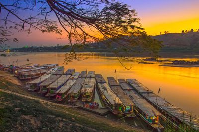 Boats moored at lakeshore during sunset