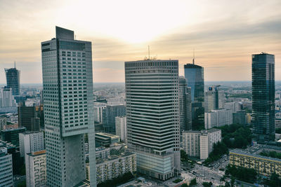 Modern buildings in city against sky during sunset