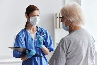 Side view of female doctor holding dentures while standing against white background