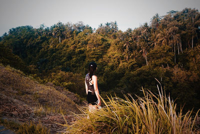 Woman looking at view while standing by plants on field