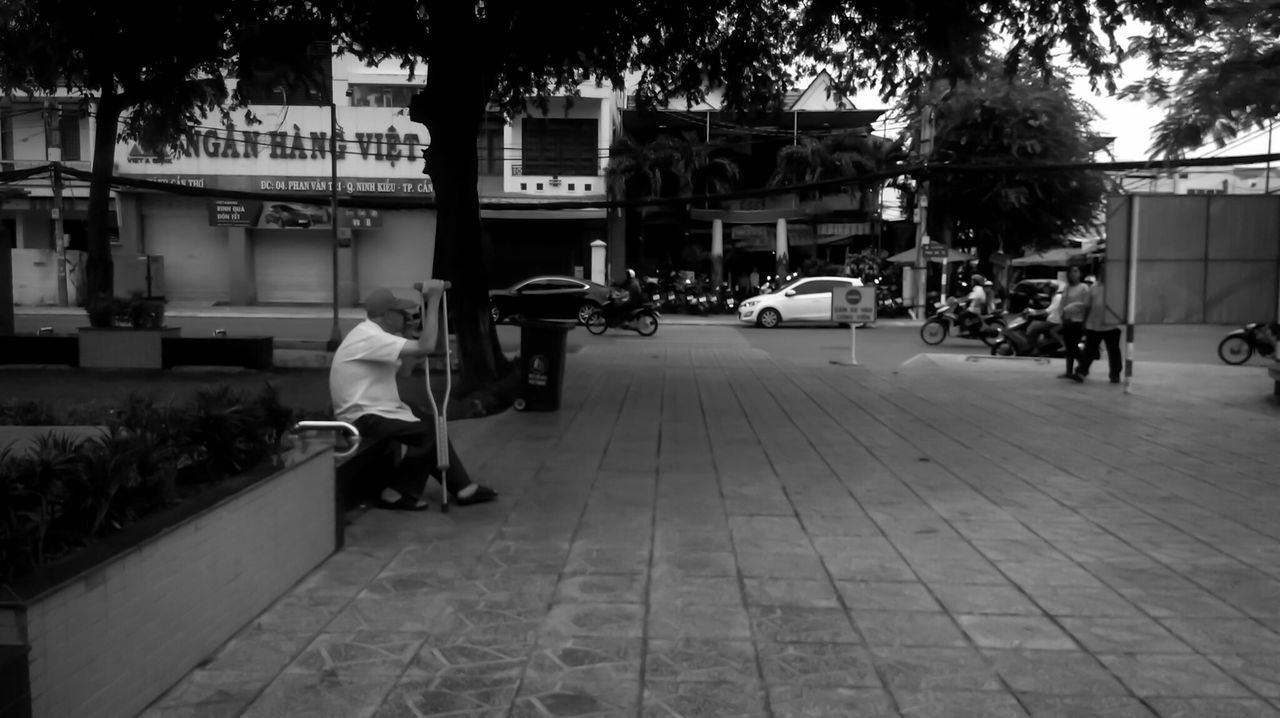 building exterior, architecture, built structure, transportation, street, tree, city, land vehicle, sidewalk, car, mode of transport, empty, city life, road, incidental people, outdoors, footpath, parking, day, cobblestone