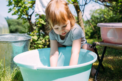 Little preschool girl helps with laundry. child washes clothes in garden