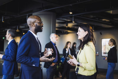 Side view of smiling male and female colleagues talking in office