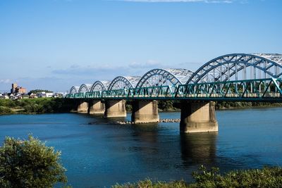 Arch bridge over river against clear blue sky