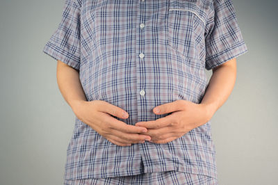 Low section of man standing against gray background