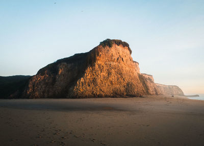 Rock formation on beach against clear sky