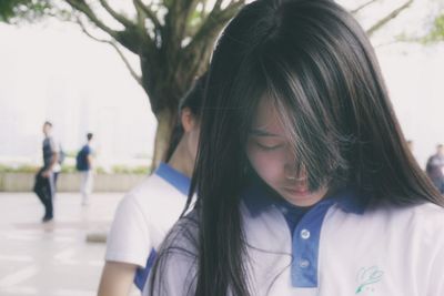 High school girl with long hair looking down at campus