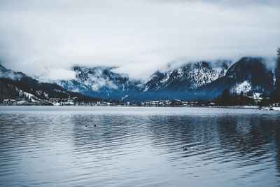 Scenic view of lake by snowcapped mountains against sky