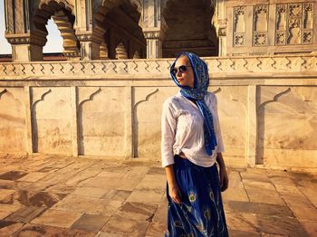 Woman wearing scarf while standing against historic building