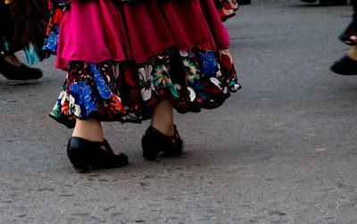 Low section of girl wearing sandals and dress while walking on road