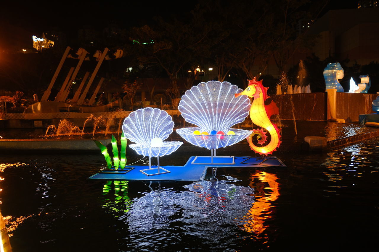 REFLECTION OF PEOPLE ON ILLUMINATED WATER AT LAKE