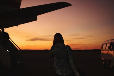 Rear view of silhouette man standing against orange sky