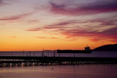 Silhouette pier over sea against sky during sunset